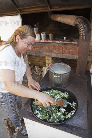 Serbian woman cooking przeno or traditional Serbian dish in her kitchen, Vrmdza, Sokobanja, Serbia