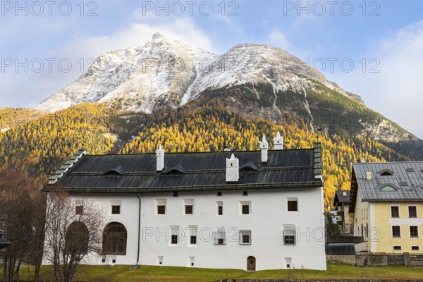Chesa Merleda in front of Piz Mezzaun, mountain peaks with snow, yellow larches (Larix), autumn colors, Engadin house, La Punt Chamue, Engadin, Graubünden, Switzerland