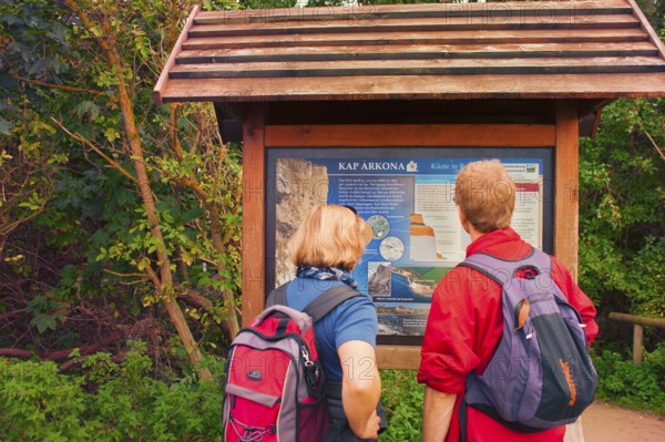 Tourist couple in front of information board of Cape Arkona, coast of Rügen, largest German island, Baltic Sea coast of Western Pomerania, famous chalk cliffs, Mecklenburg-Western Pomerania, Germany