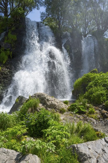 A waterfall flows over rocks surrounded by lush green vegetation in summer, Shaki Waterfall, Syunik Province, Syunik, Armenia