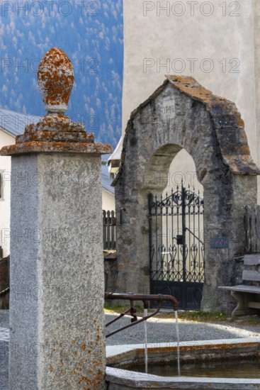 Village fountain in front of the entrance to the Firedhof, Tor, Guarda Engadin, Graubünden, Switzerland