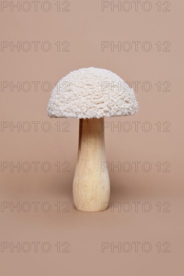 Single wooden and textile decorative mushroom object on beige background
