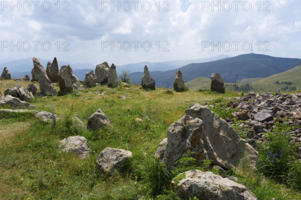 Stone formations in a meadow with a view of cloudy mountains, stone circle, megaliths, Zorats Karer, Karahundsch, Bronze Age burial ground, Sisian, Sisian, Sjunik province, historic Sangesur, Armenia