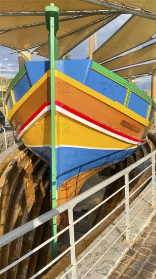 Monument to traditional fishing boats disused jacked up typical colorful painted old fishing boat from Gozo at Gozo Harbour, Mgarr Harbour, Gozo, Malta