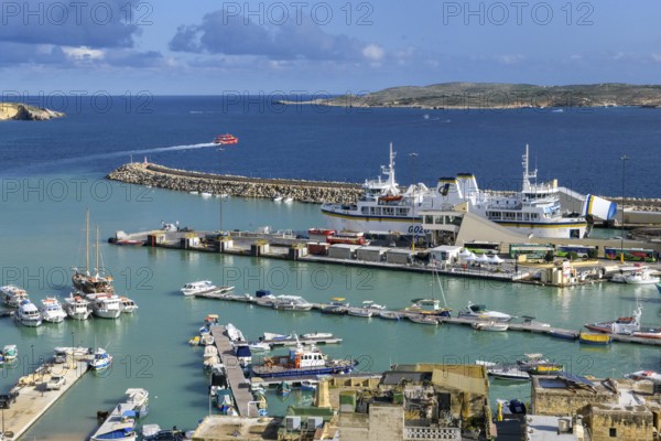 View from an elevated position of Mgarr harbour on the island of Gozo, large car ferry with open flap for entry and exit, small red fast ferry for passenger traffic on the left in the background, Gozo, Malta