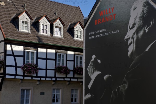 Huge poster with Willy Brandt portrait on a fire wall of the Willy Brandt Forum next to a half-timbered house, Altstadt, Unkel, Rhineland-Palatinate, Rhineland, Germany