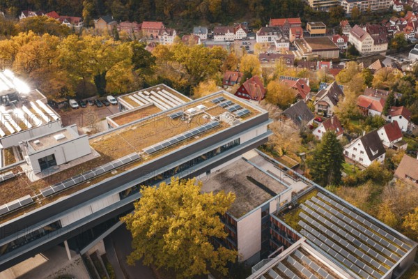 Aerial view of building roofs with solar cells and surrounding autumnal villages, Calw District Office, Calw, Germany