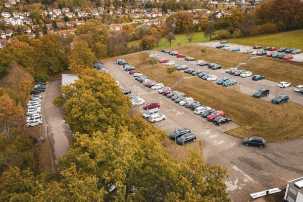 Large parking lot with various cars surrounded by slightly coloured autumn trees, Calw District Office, Calw, Germany