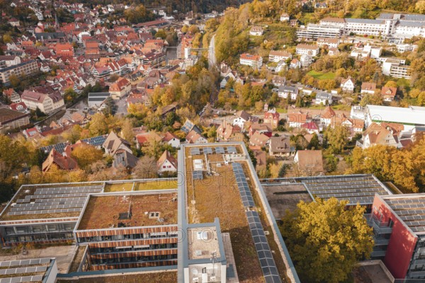 Panorama of a city in autumn colors, modern buildings with solar cells in the foreground, Calw District Office, Calw, Germany