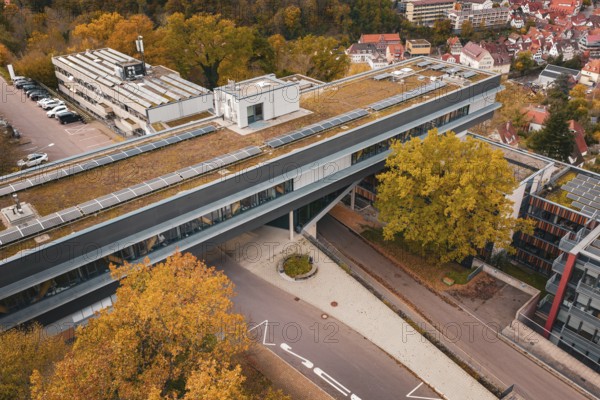 Roof view of a modern building with solar panels and surrounding autumn trees, Calw District Office, Calw, Germany