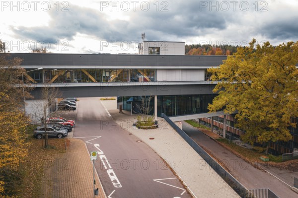Modern building with covered bridge connection and colorful trees, Calw District Office, Calw, Germany