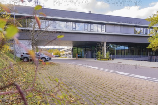 Street scene in front of a modern office building surrounded by autumn leaves and a parking lot, Calw District Office, Calw, Germany