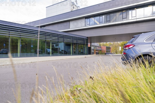 Modern office building with grey façade, surrounded by autumn grass and a parking lot, Calw District Office, Calw, Germany