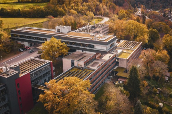 Autumn aerial view of a large building complex in the middle of forest and village, Calw District Office, Calw, Germany