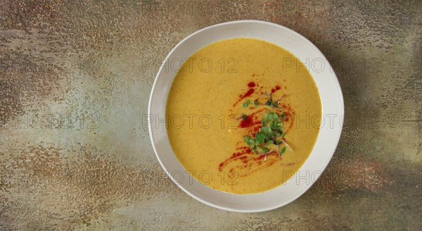 Pumpkin cream soup, in a white bowl on a textured background, top view, homemade, no people, rustic style