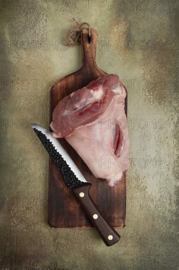 Raw pork knuckle, on a wooden chopping board, close-up, top view, no people
