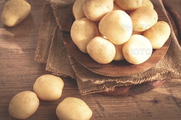 Boiled new potatoes, in a wooden bowl, on a rustic table, natural light, no people
