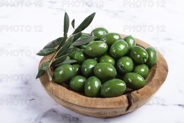Halkidiki olives, classic Greek green olives, in a wooden bowl, on a marble table, no people