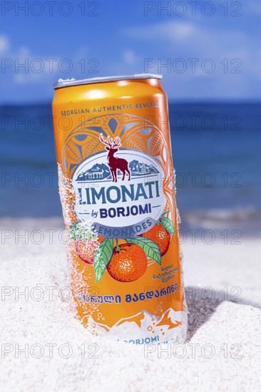 Adjara mandarin lemonade, Borjomi, aluminum can, on the beach sand, against the background of the sea, sunlight, close-up