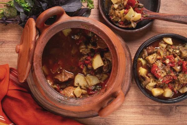 Chanakhi, a Georgian dish. in a clay pot, on a wooden table, stewed meat with vegetables, homemade, no people