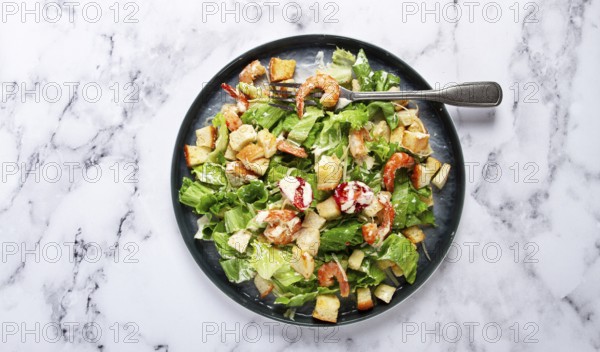 Caesar salad, with shrimp, on a marble background, top view, no people