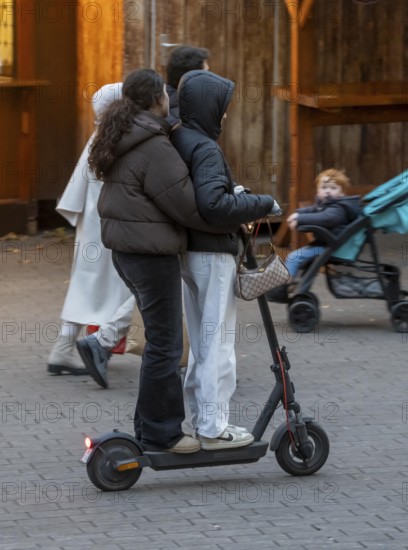 City center, shopping street, Kettwiger Straße pedestrian zone in Essen, 2 young woman on an e-scooter, electric scooter, in front of the opening of the Christmas market, North Rhine-Westphalia, Germany
