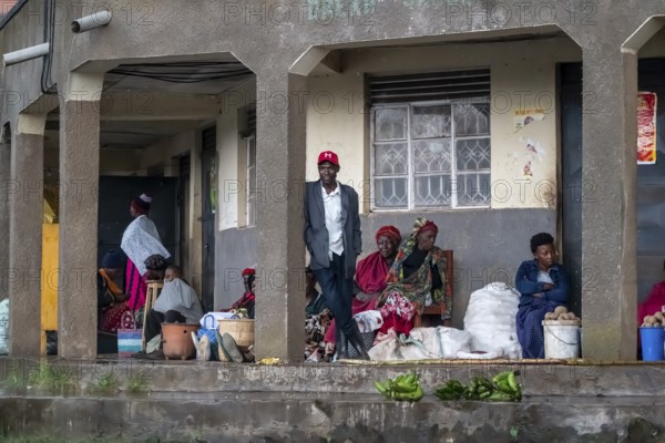 Street scene, people waiting outside houses for the rain to end selling vegetables, Kisoro, Uganda