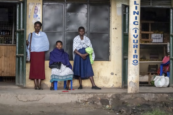 Street scene, people waiting outside houses for the rain to end, Kisoro, Uganda