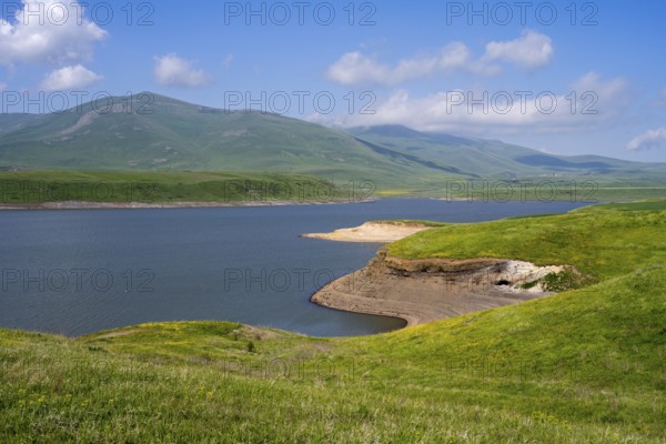 A calm lake surrounded by green hills and mountains under a blue sky with clouds, Spandaryan Reservoir, Spandarian, fed by Vorotan River, Vorotan, Syunik Province, Syunik, Armenia