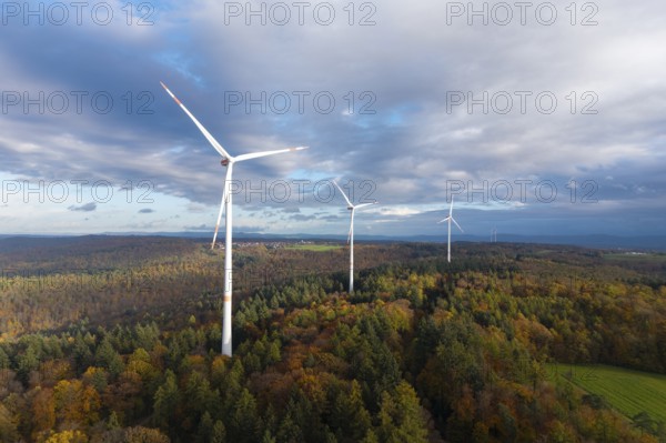 Wind turbines tower above an autumnal forest under a cloudy sky, near Schorndorf, Remstal, Rems-Murr-Kreis, Baden-Württemberg, Germany