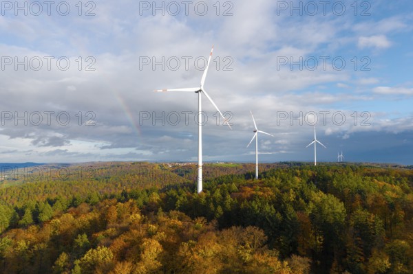 Wind turbines rise above an autumnal forest with a rainbow in the background, near Schorndorf, Remstal, Rems-Murr-Kreis, Baden-Württemberg, Germany