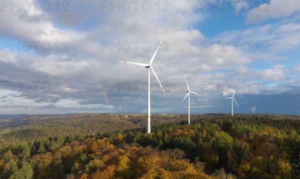 Wind turbines stand over an autumnal forest with a rainbow in the sky, near Schorndorf, Remstal, Rems-Murr-Kreis, Baden-Württemberg, Germany