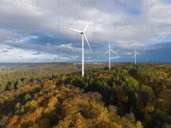 A wind farm rises above an autumnal forest under a cloudy sky, near Schorndorf, Remstal, Rems-Murr-Kreis, Baden-Württemberg, Germany