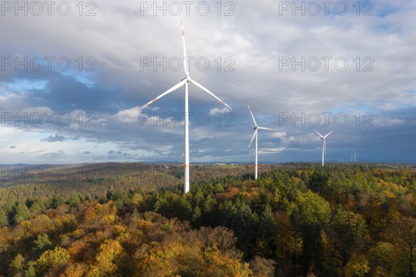 Wind turbines stand in a colorful autumn forest under a changing sky, near Schorndorf, Remstal, Rems-Murr-Kreis, Baden-Württemberg, Germany