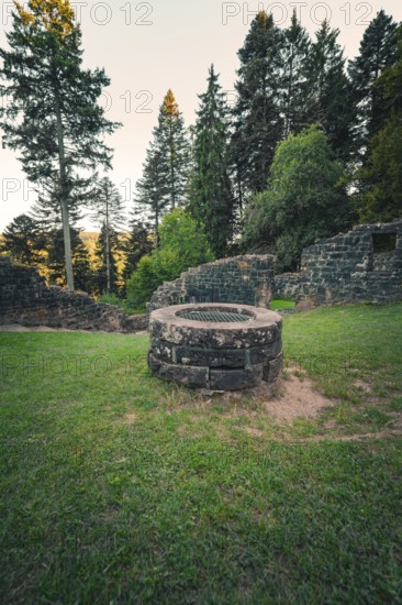 A historic well surrounded by ruins, surrounded by forest and illuminated by soft evening light, Mandelberg Castle Ruins, Pfalzgrafenweiler, Freudenstadt District, Germany