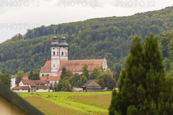 Church with red roofs nestled in green forest and meadow landscape, ZFP Zwiefalten, Reutlingen district, Germany