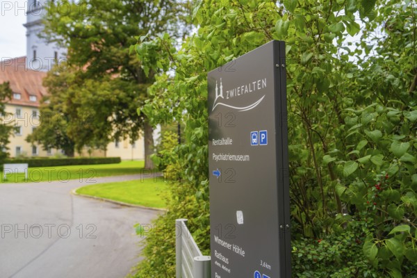A sign with the reference to Zwiefalten stands against a background of green plants and a building, ZFP Zwiefalten, Reutlingen district, Germany