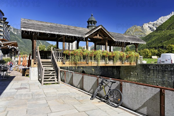 Old wooden bridge decorated with flowers that crosses the glacial river Arve, Chamonix-Mont-Blanc, Haute-Savoie, France