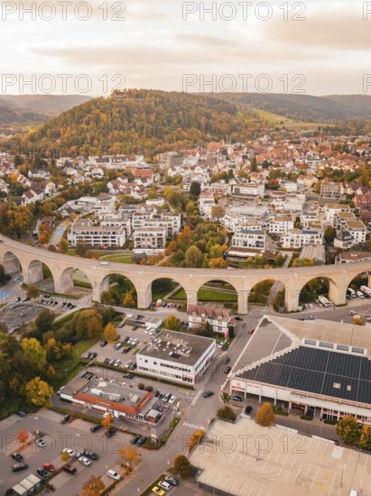 Aerial view of the city with an elongated bridge surrounded by autumn trees, hills and an urban landscape, Nagold, Black Forest, Germany