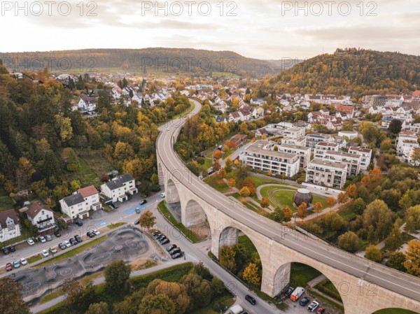 Curvy bridge over an urban road surrounded by colorful autumn trees and houses, Nagold, Black Forest, Germany