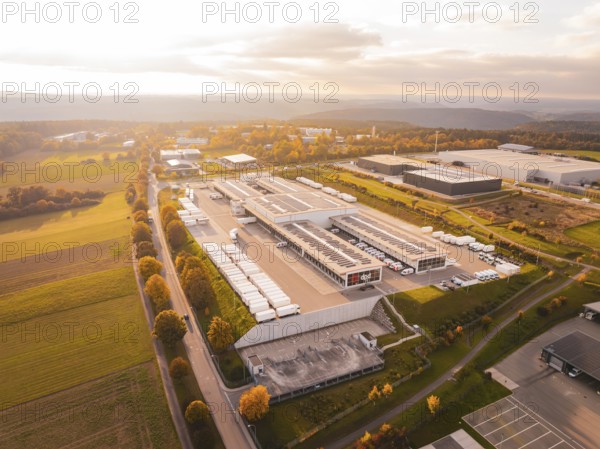 Industrial park with numerous buildings surrounded by green fields and warm skies, Nagold, Black Forest, Germany
