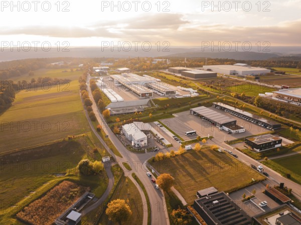 Business park from above, surrounded by countryside and roads, everything in soft evening light, Nagold, Black Forest, Germany