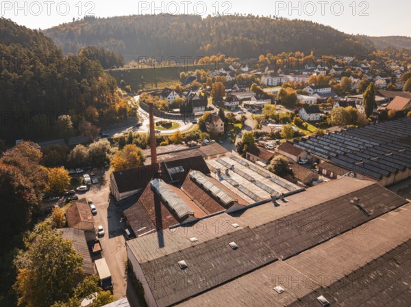 An industrial area with factory buildings and a chimney, nestled in an autumn landscape, Nagold, Black Forest, Germany