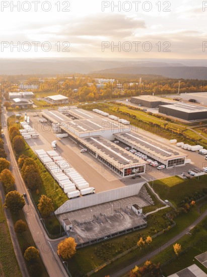 Extensive industrial park with parked trucks and buildings, in colorful late afternoon light, Nagold, Black Forest, Germany