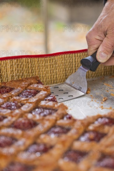 Hand cut a piece of raspberry pastry with a scraper on a tray, Streuobstmarkt, Sindelfingen, Böblingen district, Germany