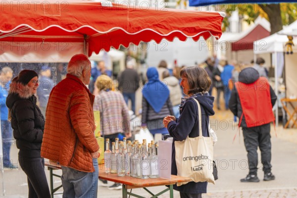 Woman engaged in conversation at a stand with bottles and decorations at a market, traditional fruit market, Sindelfingen, Böblingen district, Germany