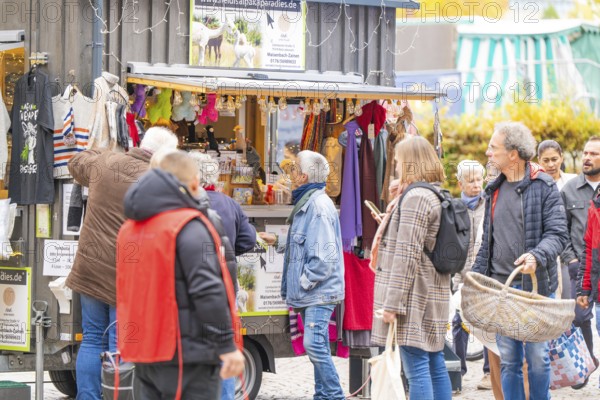 Busy market stand with people inspecting clothes and accessories, Streuobstmarkt, Sindelfingen, Böblingen district, Germany