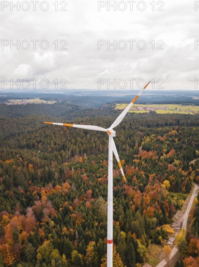 Tall wind turbine above autumnal forest and fields, Simmersfeld wind farm, Germany