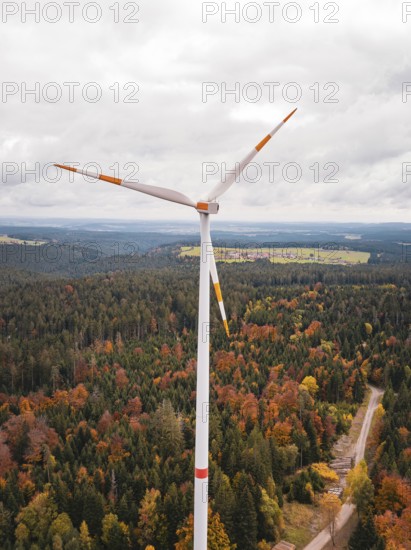 Wind power plant over autumn-colored forest and narrow path, Simmersfeld wind farm, Germany