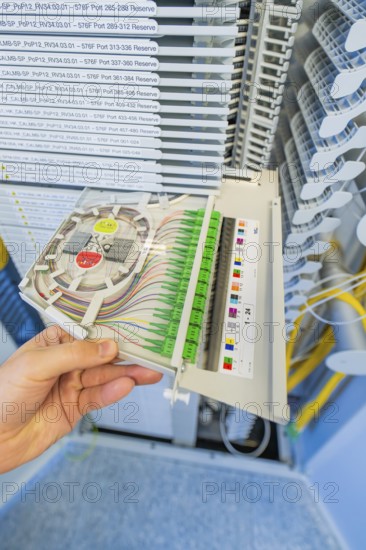 Hand holding a fiber optic cabling module in a technical environment, optical fiber